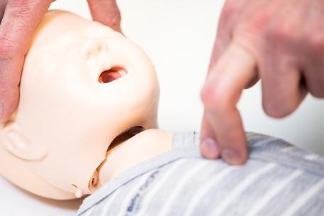 Someone performing first aid on a baby dummy,