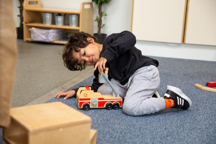 child with truck in toddler room at nursery
